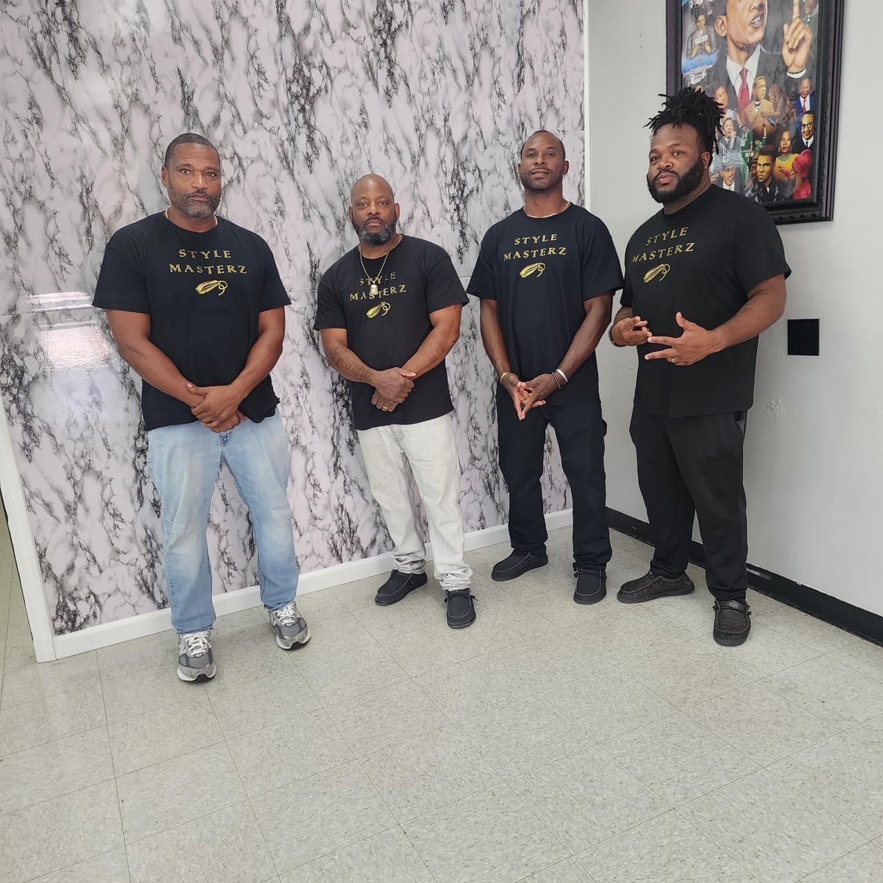 The Style Masterz barbers lined up in branded tees against the marble wall