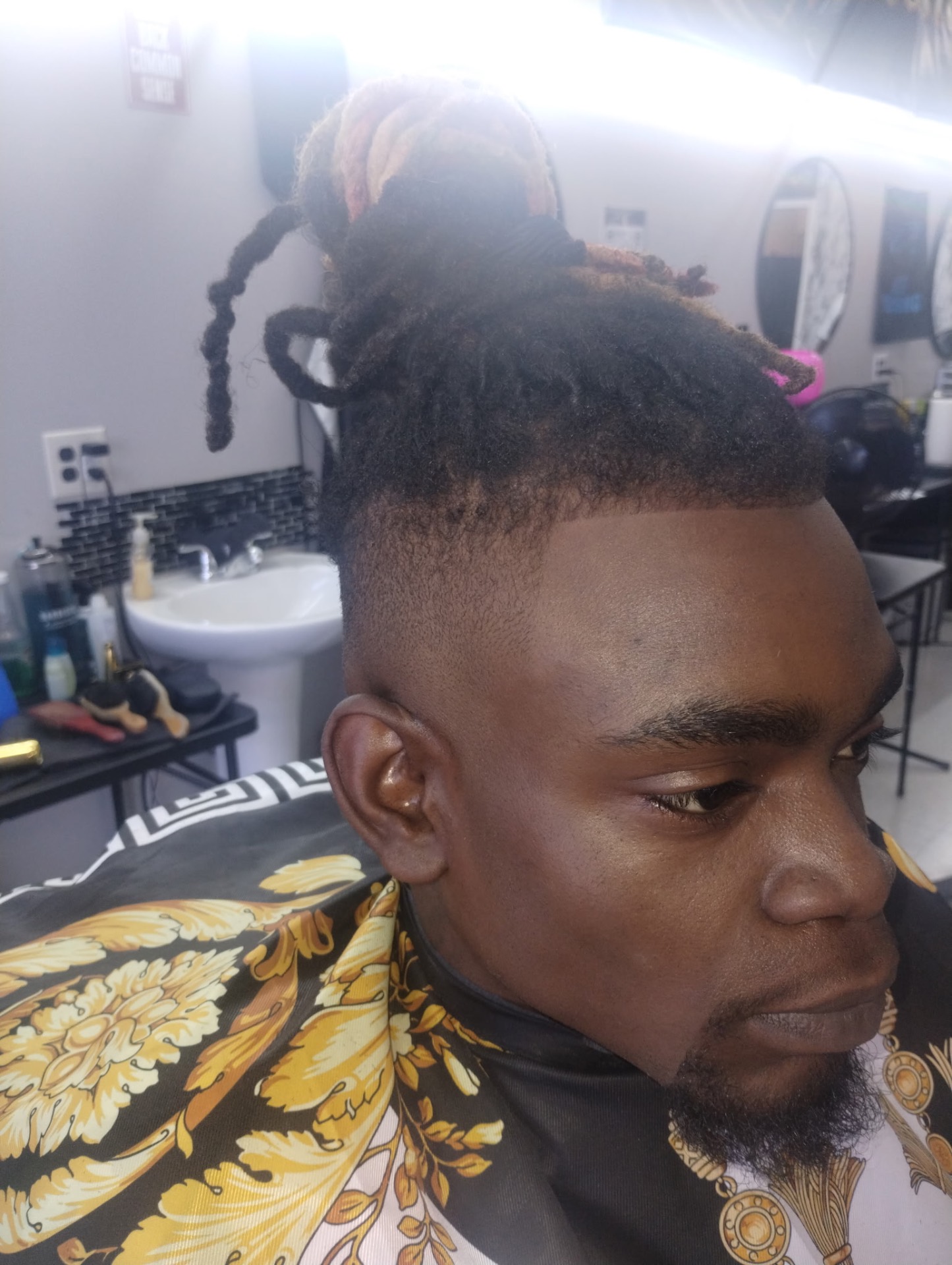 Loc top knot with bald skin fade and shaped beard